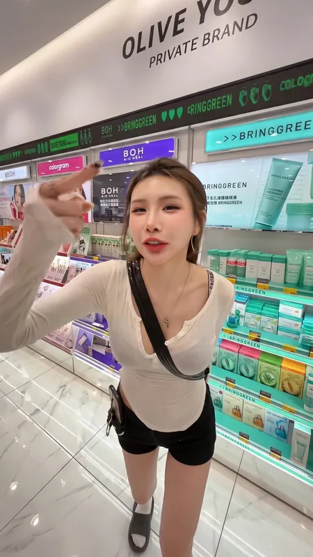 화장품 매장 진열대 앞에서 손가락으로 가리키는 여성의 영상 화면